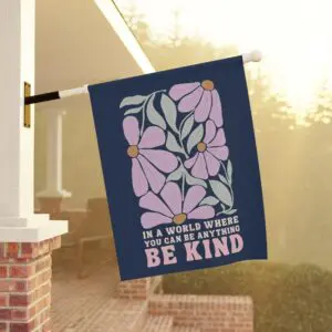 'Be Kind' floral garden flag displayed outdoors on a porch