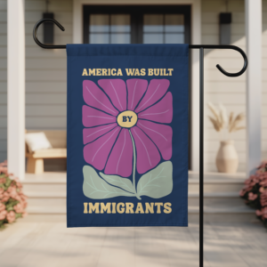 Floral garden flag with 'America Was Built By Immigrants' text, displayed outdoors
